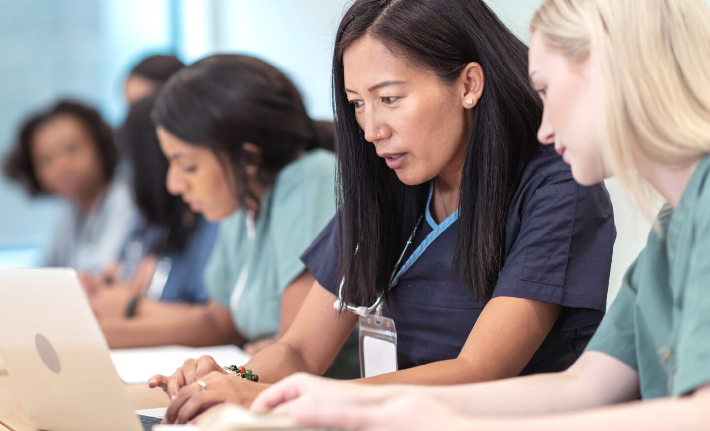 A group of nurses working at a table on laptops.