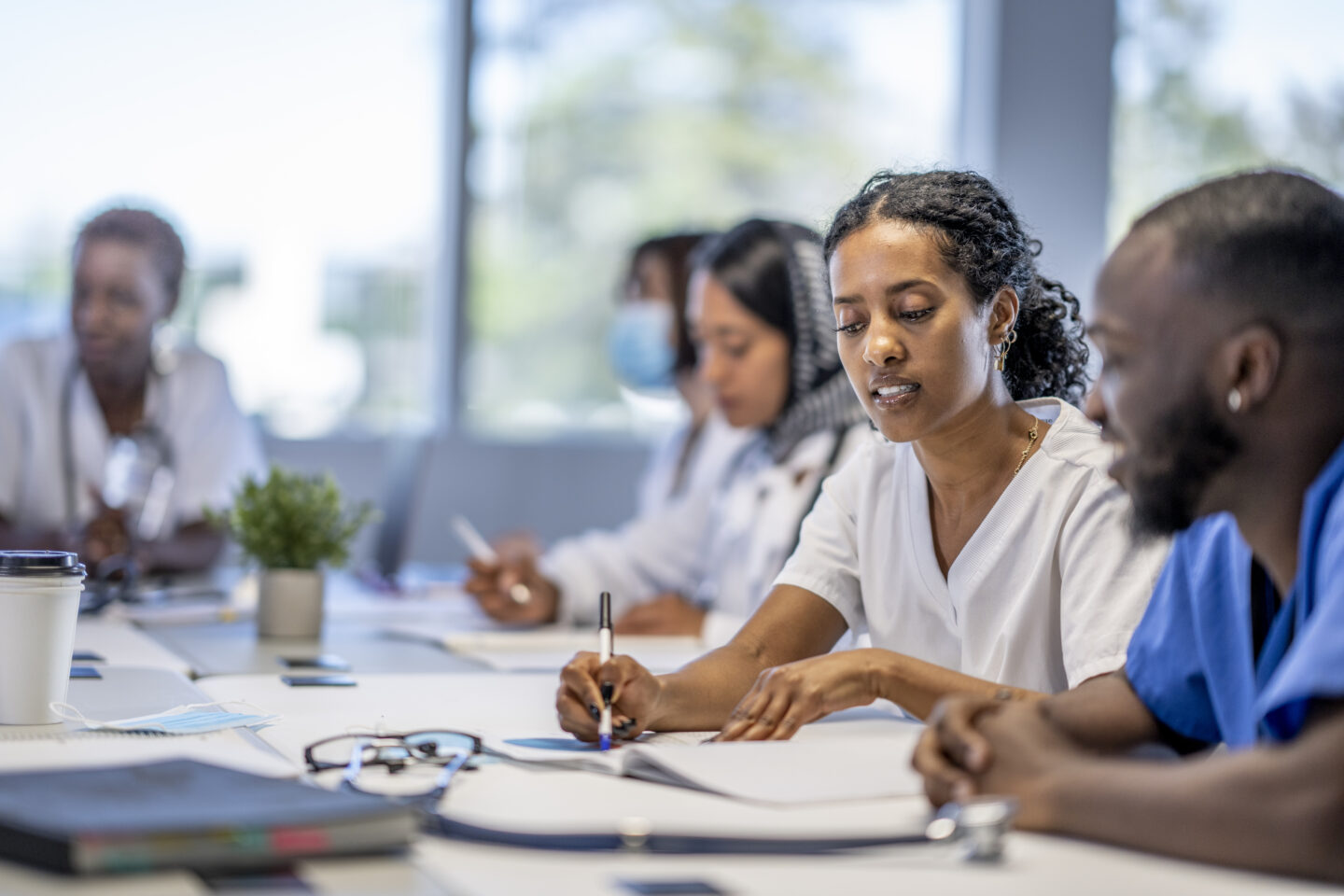 A small group of medical professionals sit around a boardroom table as they meet to discuss patient cases.